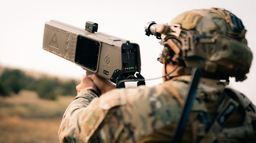Operator shouldering a Dronebuster handheld counter-UAS system in the field
